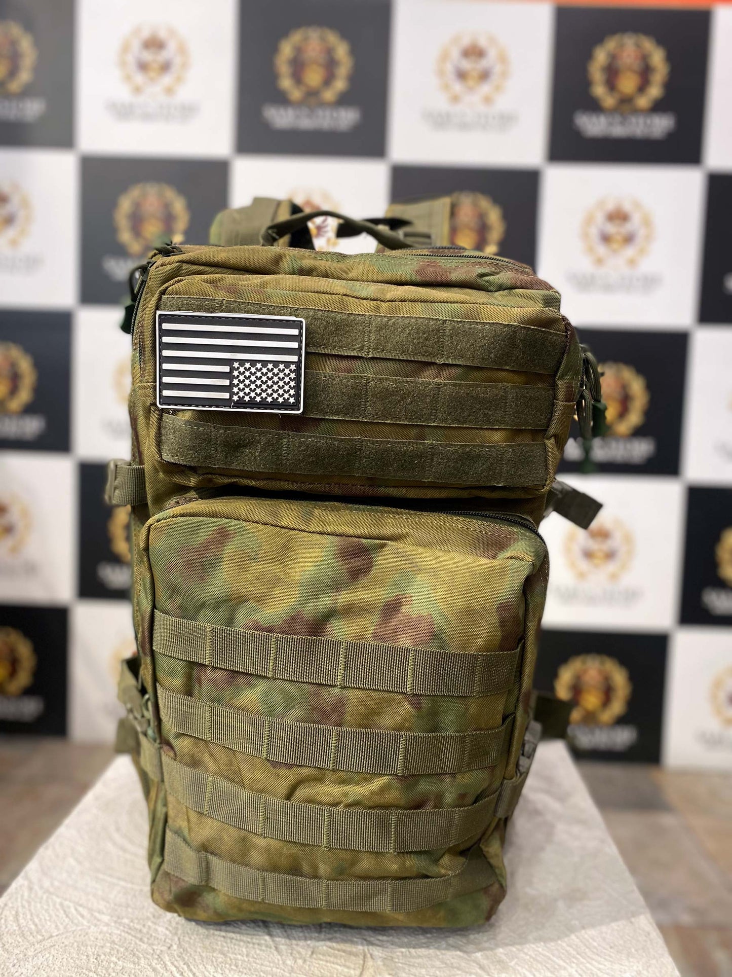 "Front view of military-style camouflage unisex backpack with tactical straps and USA flag patch"