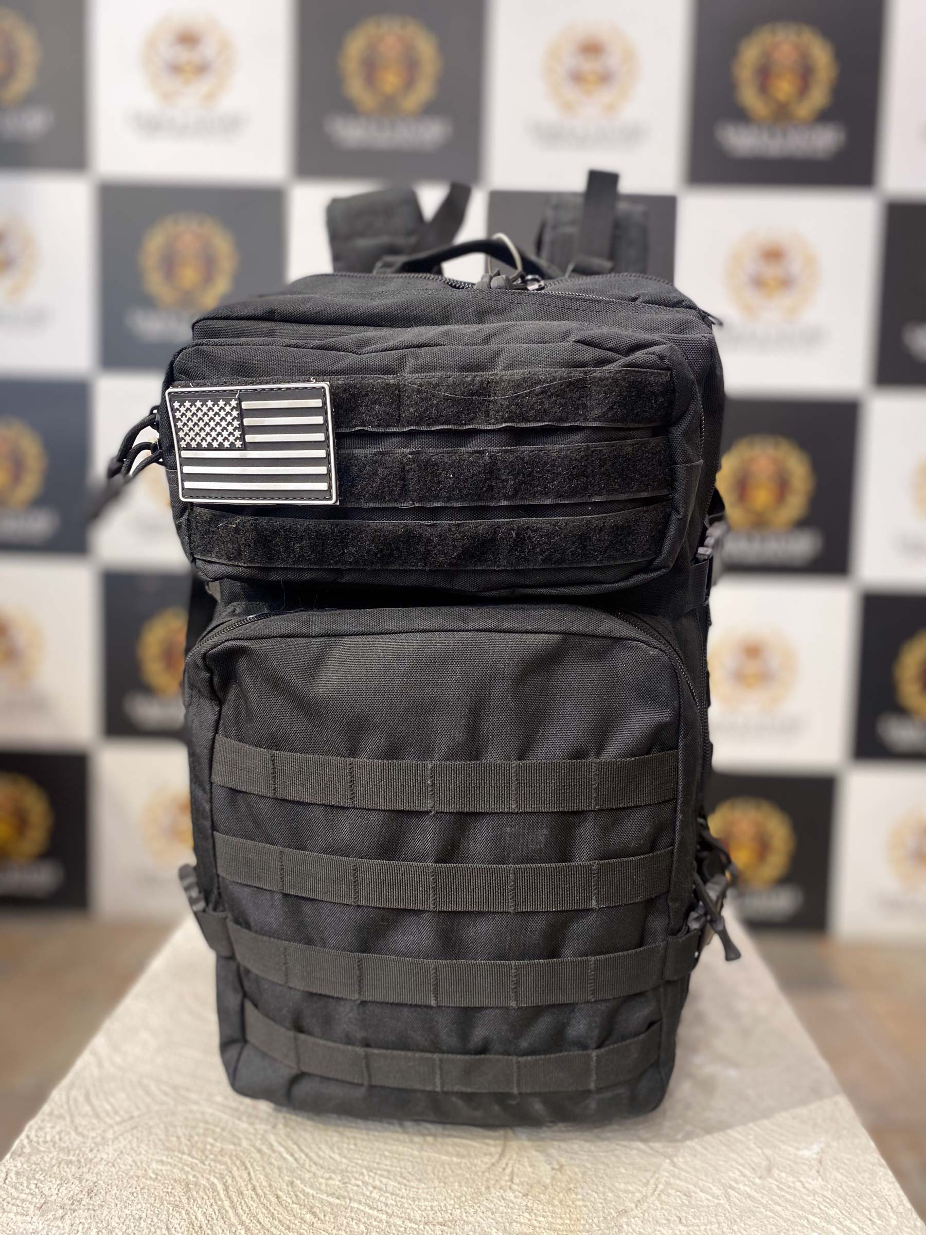 Front view of black tactical backpack with US flag patch and utility compartments