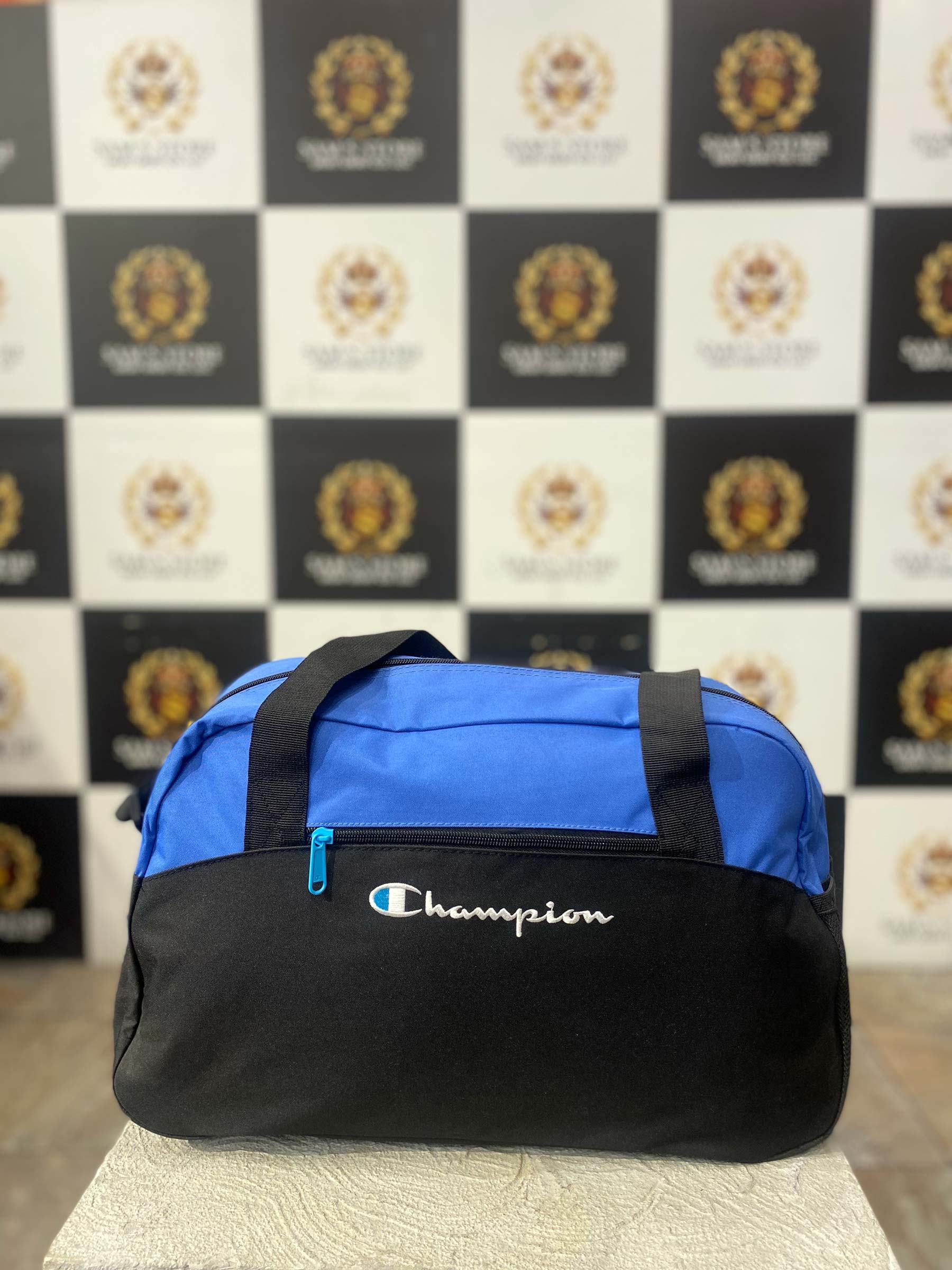 Front view of Champion duffle bag in blue and black with logo and front zipper pocket