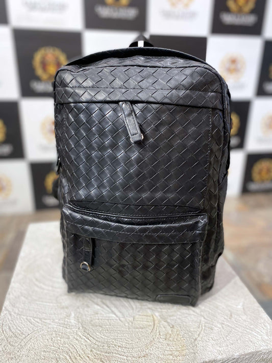 Front view of black woven-style leather unisex backpack with front zipper pocket and sleek finish